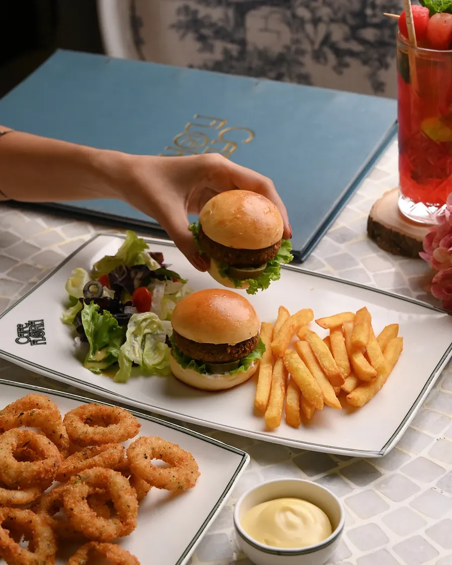 A burger with fries and onion rings beside the blue menu